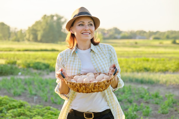 Portrait rustique de femme mature avec panier d'oeufs au pré