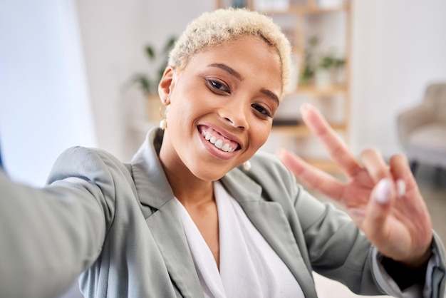 Photo portrait de selfie et femme d'affaires avec des mains de paix sourire et emoji pour la photo de profil de médias sociaux heureux travailleur v signe et prend une photo lors d'un appel vidéo pour le bonheur et le visage de la connexion d'entreprise