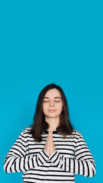 Portrait serein d'une belle jeune femme méditant avec les yeux fermés et les paumes paix intérieure et Re