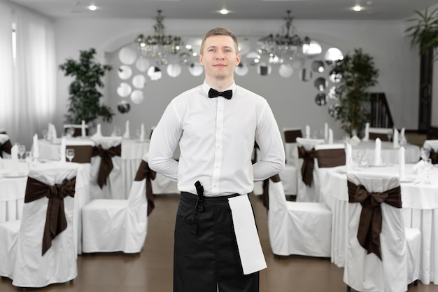 Portrait d'un serveur masculin en chemise blanche dans la salle de banquet d'un restaurant