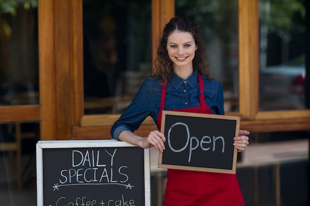 Portrait de serveuse debout avec tableau noir et menu