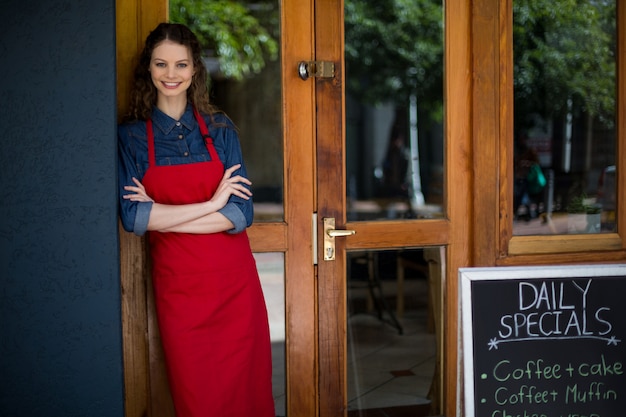 Portrait de serveuse souriante debout avec les bras croisés