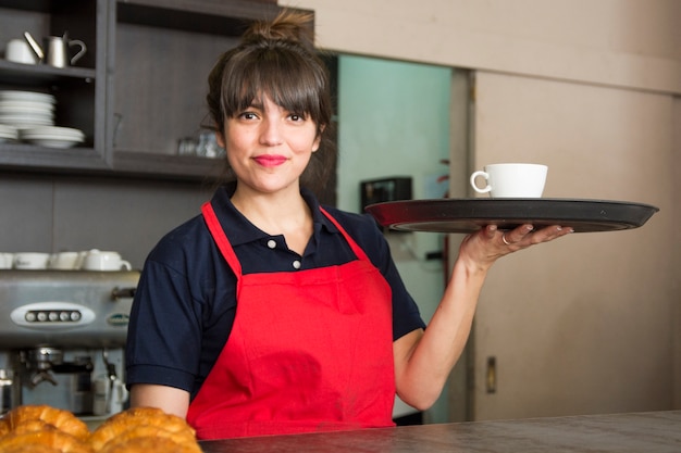 Photo portrait de serveuse souriante tenant un plateau avec une tasse de café