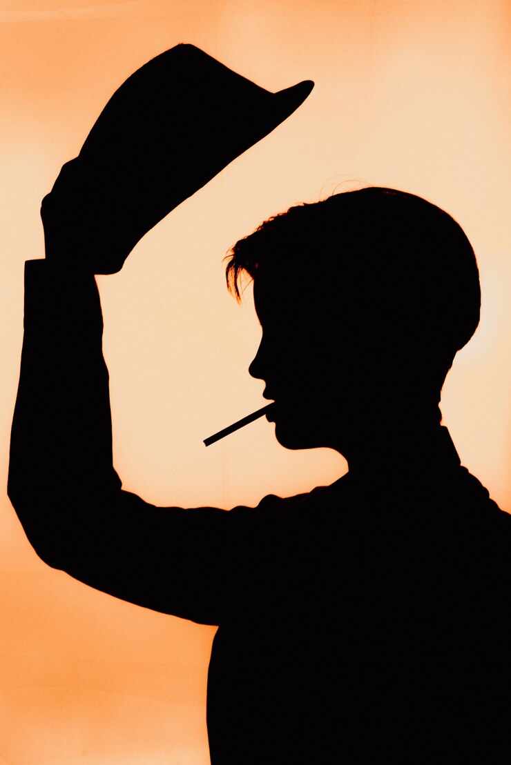Photo portrait d'une silhouette d'une jeune fille au chapeau avec une cigarette.