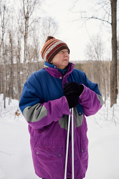 Portrait d'un skieur senior dans une forêt d'hiver