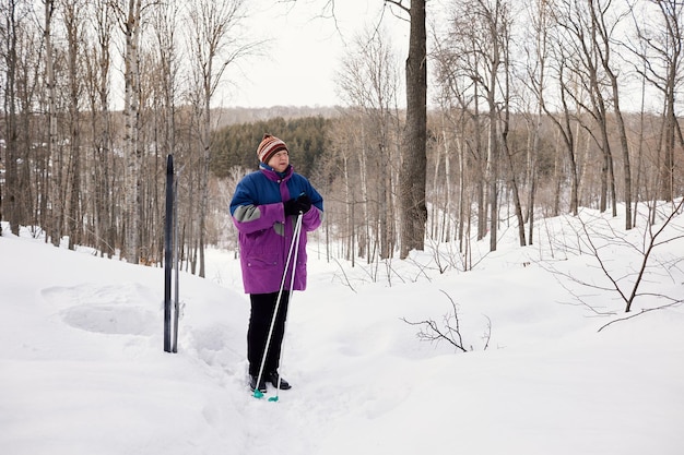 Portrait d'un skieur senior dans une forêt d'hiver