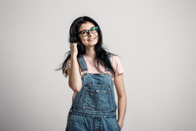 Portrait de smart belle fille brune à lunettes avec maquillage naturel, sur fond gris.