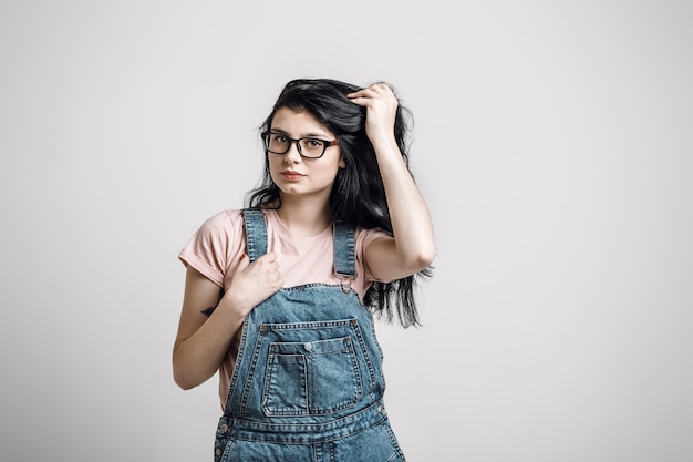 Portrait de smart belle fille brune à lunettes avec maquillage naturel, sur fond gris.