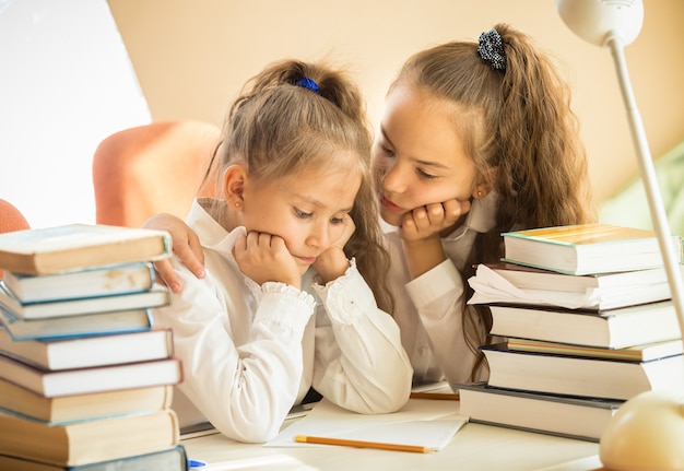 Portrait de sœur aînée apaisante plus jeune tout en faisant ses devoirs