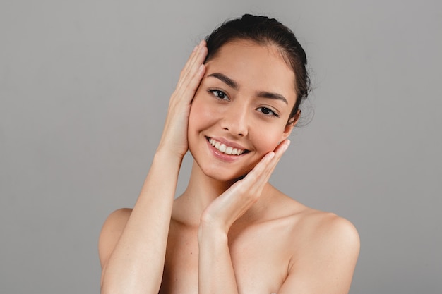 Portrait de soins de la peau de belle femme avec la main sur fond gris. Prise de vue en studio.