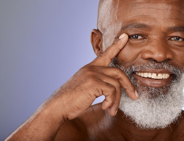 Portrait de soins de la peau esthétique senior et homme noir avec sourire pour le bien-être santé et dermatologie zoom Modèle cosmétique mature heureux et africain touchant le visage sur la maquette marketing du studio violet