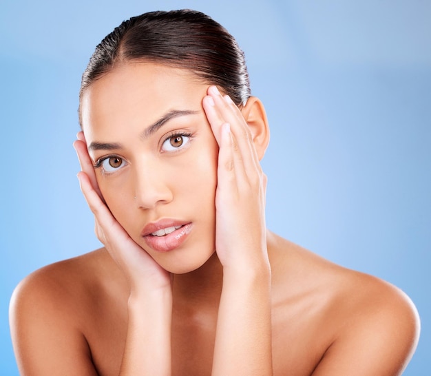 Portrait de soins de la peau ou d'un modèle en studio après une routine de beauté ou de soins du visage sur fond bleu avec espace de maquette Fille en bonne santé de luxe ou belle femme touchant le visage pour l'amour de soi ou les soins personnels