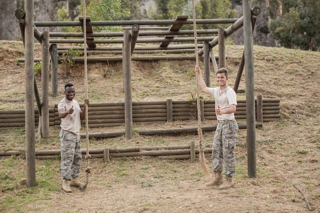 Portrait de soldat militaire montrant les pouces tout en maintenant la corde pendant la formation du camp d'entraînement