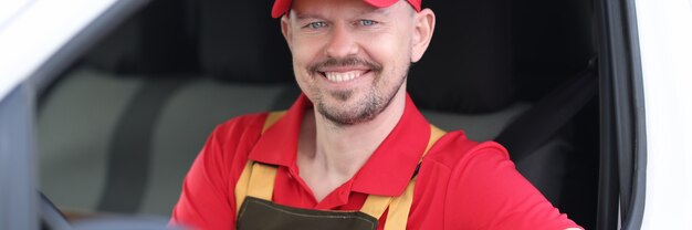 Portrait souriant d'un conducteur de messagerie masculin tenant des documents dans la fenêtre de la voiture