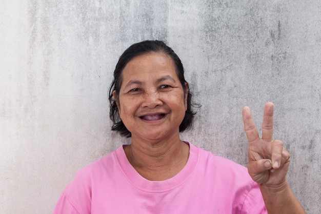 Portrait souriant de femme thaïlandaise et montrant le signe V