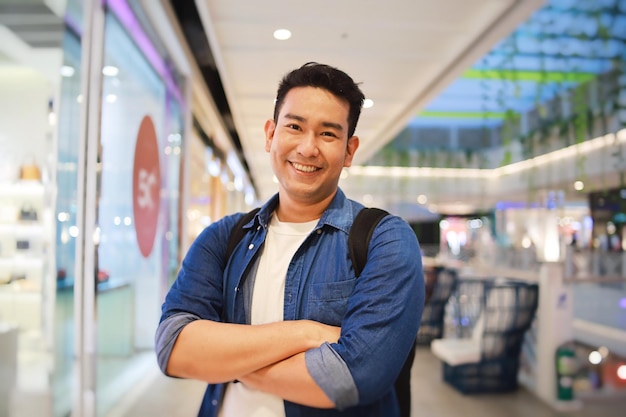 Portrait souriant homme asiatique en chemise décontractée debout dans un supermarché