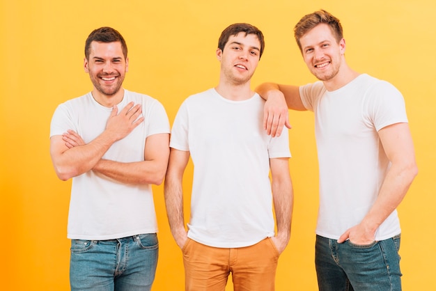 Portrait de souriant trois amis de sexe masculin en t-shirt blanc en regardant la caméra