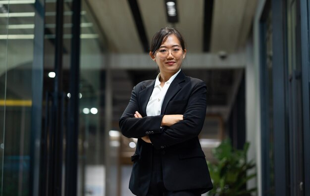 Photo portrait souriante jeune femme d'affaires confiante debout au bureau à la maison regardant la caméra les bras croisés