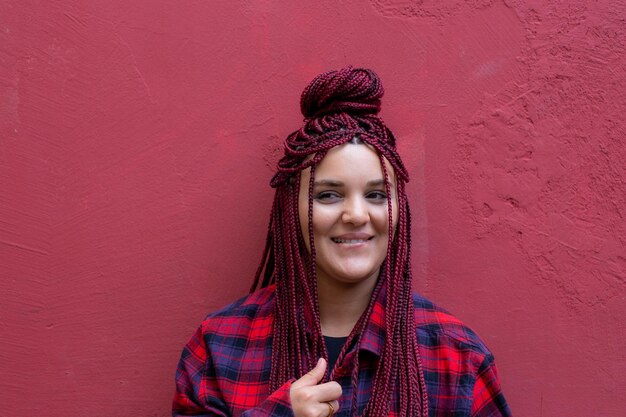 Portrait souriante jeune femme avec des dreadlocks rouges portant une chemise à carreaux rouge