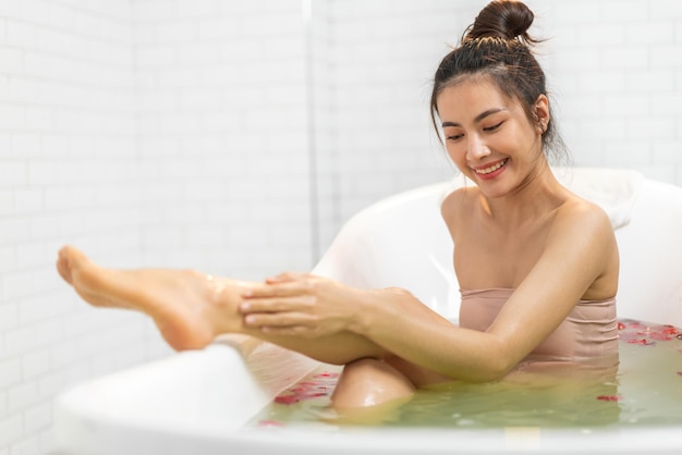 Portrait de sourire de beauté heureuse jolie femme asiatique propre traitement de spa peau blanche fraîche et saine profiter de la détente en prenant une douche et un bain avec un spa en mousse à bulles dans la baignoire de la salle de bain