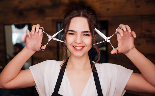 Portrait, de, sourire, belle femme, coiffeur, à, tablier noir, regarder appareil-photo