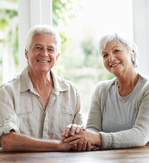 Portrait sourire et couple de personnes âgées se tenant la main pour soutenir l'amour et se détendre ensemble à la maison Heureux vieil homme femme et coup de main pour les soins de confiance et la loyauté envers le respect et la gratitude du partenaire de vie