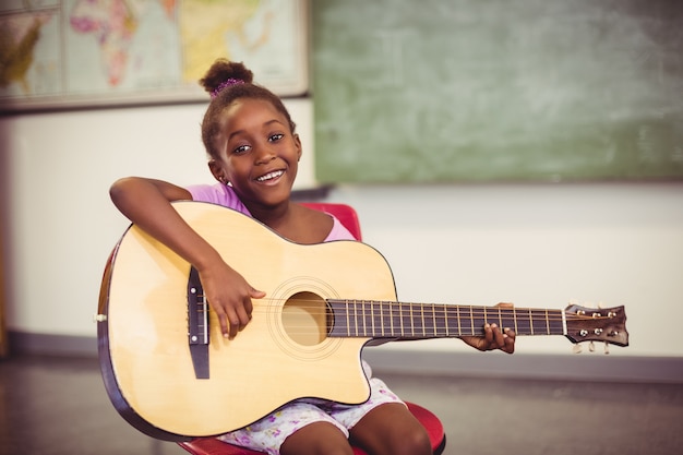 Portrait, de, sourire, écolière, jouer guitare, dans, classe