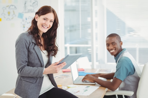 Portrait de sourire des gens d&#39;affaires à l&#39;aide de tablette numérique et ordinateur portable