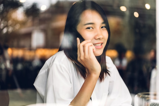 Portrait de sourire heureux belle femme asiatique se détendre à l'aide de smartphone numérique.