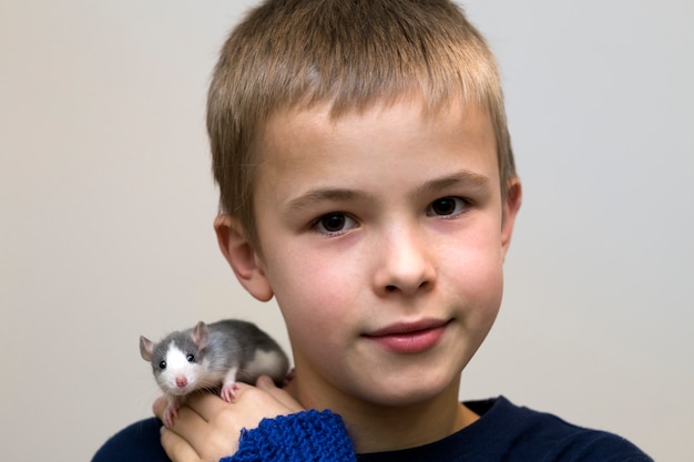 Portrait de sourire heureux drôle mignon bel enfant garçon avec hamster souris pour animaux de compagnie blanc sur l'épaule sur fond d'espace copie légère.