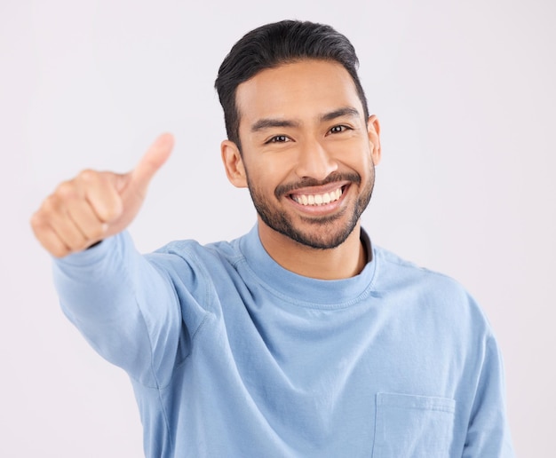 Portrait sourire et homme asiatique en studio avec le pouce levé main ou signe de remerciement sur fond gris Visage heureux et homme japonais avec doigt emoji pour oui vote ou examen positif succès ou accord