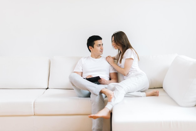 Portrait de sourire joyeux jeune homme et femme câlin sur fond de salon blanc en se regardant. Heureux couple embrasser rire s'amuser ensemble. Concept de bonnes relations