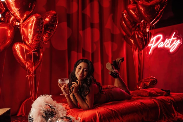 Portrait de sourire sexy fille asiatique glam maquillage en lingerie de dentelle rouge allongé sur le lit à la Saint Valentin