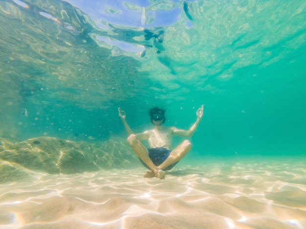 Portrait sous-marin d'un homme en position de yoga sous l'eau dans la mer