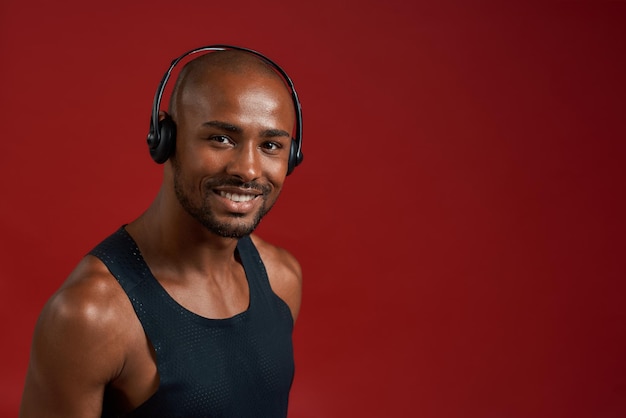 Portrait de sportif heureux de bel homme afro-américain gai dans les écouteurs regardant la caméra