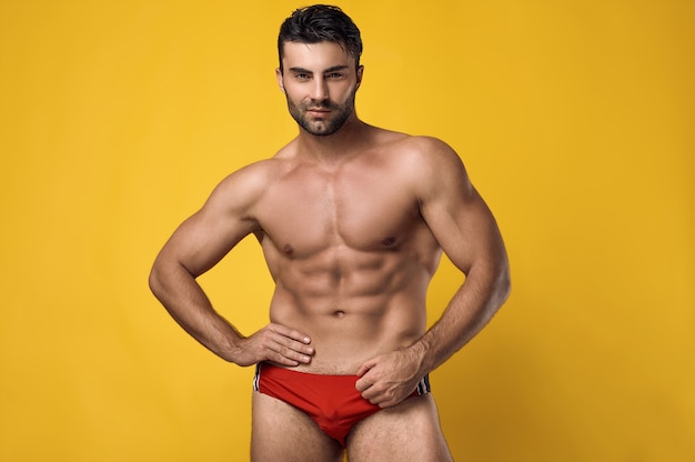 Portrait en studio d'un bel homme musclé bronzé brutal portant un sous-vêtement rouge sur un jaune