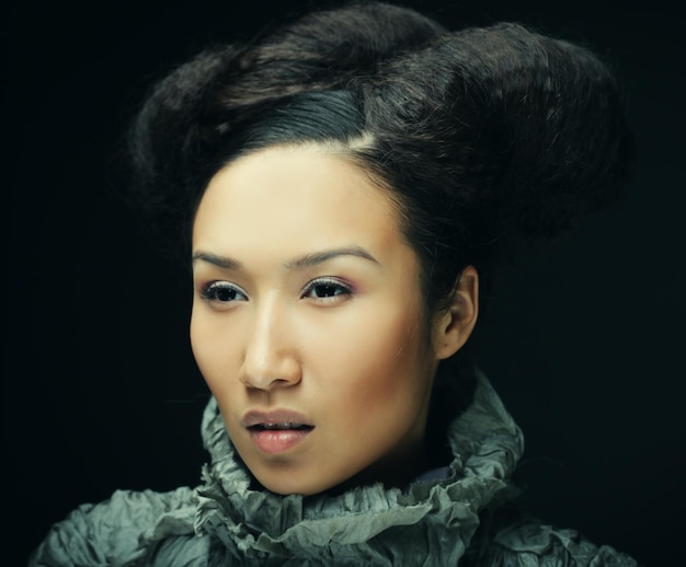 Portrait en studio de belle femme en robe grise avec une coiffure de mode Concept de mode et de beauté