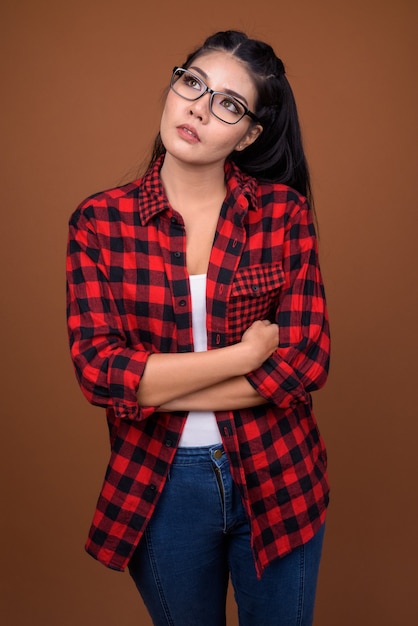 Portrait en studio de la belle jeune femme asiatique hipster pensant