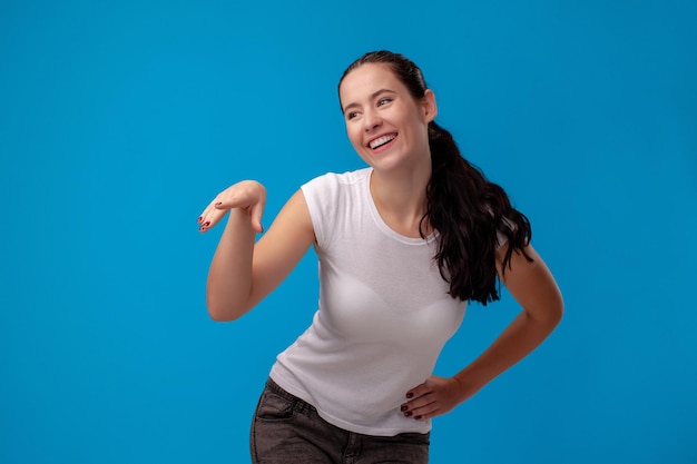 Portrait en studio d'une belle jeune femme vêtue d'un t-shirt blanc sur fond de mur bleu, les gens s...