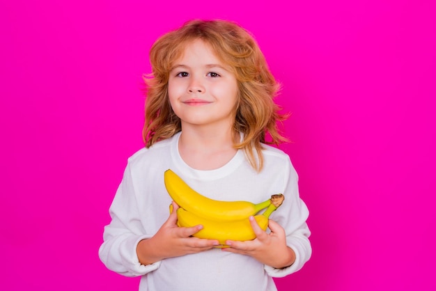 Portrait en studio d'un enfant mignon avec un fruit du dragon isolé sur un espace de copie de fond rose