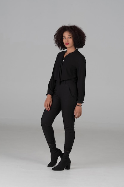 Portrait en studio d'une femme afro-américaine en robe noire sur fond gris