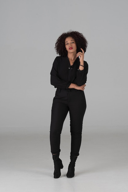 Portrait en studio d'une femme afro-américaine en robe noire sur fond gris