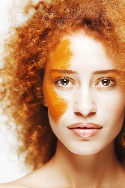 Portrait en studio de femme aux cheveux bouclés rougeâtres et maquillage orange Tourné en studio sur fond blanc