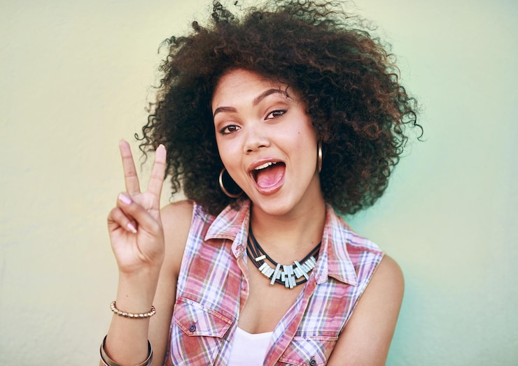 Photo portrait de studio et fille avec signe de paix mode et réaction avec v ou geste de la main emoji modèle féminin et accessoires pour un look élégant boucles d'oreilles et colliers ou bijoux sur fond blanc