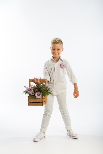 Portrait en studio de garçon caucasien blond à la mode avec panier en bois de fleurs,