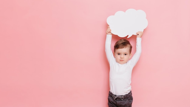 Portrait en studio d'un garçon heureux avec un tableau blanc propre en forme de nuage