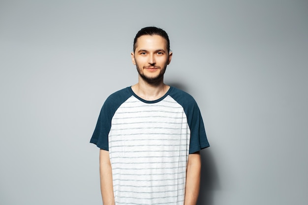 Portrait en studio d'un gars sérieux sur fond gris portant une chemise blanche avec du bleu