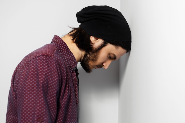 Portrait en studio de gars triste sur une surface blanche.