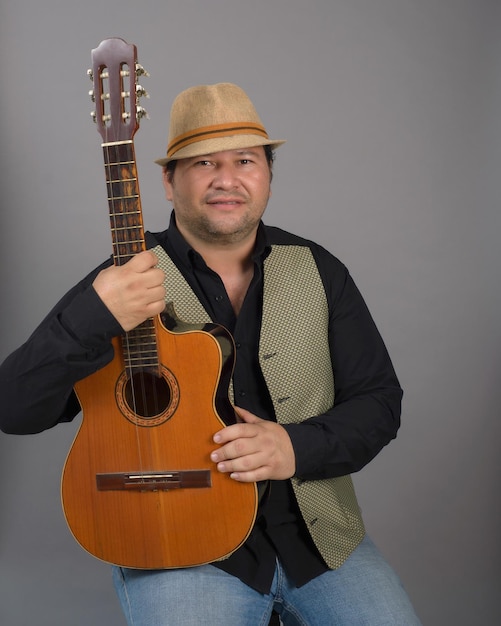 Portrait en studio d'un homme assis portant un chapeau et tenant un vieux tres cubain