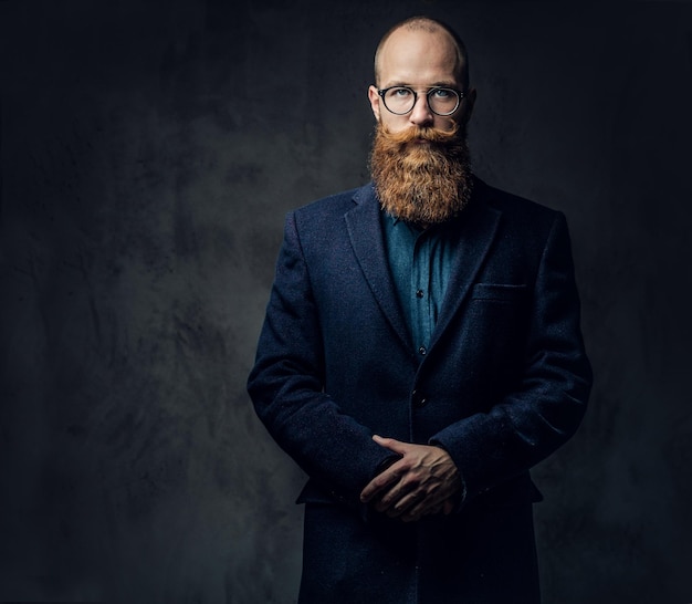 Portrait en studio d'homme barbu rousse dans des lunettes vintage vêtu d'une veste en laine.